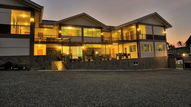 A multi-story building with a covered outdoor area, a staircase leading to the upper floors, and a gravel driveway. - Hanan Hotel Tagaytay (Tagaytay)