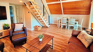 A spacious loft with a wooden ceiling, a staircase, and a dining area.