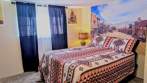 Une chambre à coucher avec un lit, des rideaux, une lampe et un tableau au mur.