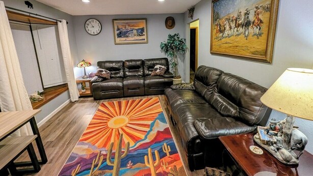 Un salon avec un canapé en cuir, un tapis coloré, une horloge et un tableau accroché au mur.
