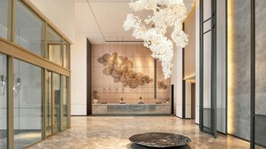 Un hall d’entrée moderne doté d’un comptoir de réception, de cloisons en verre, d’un sol en marbre et d’un luminaire décoratif suspendu.