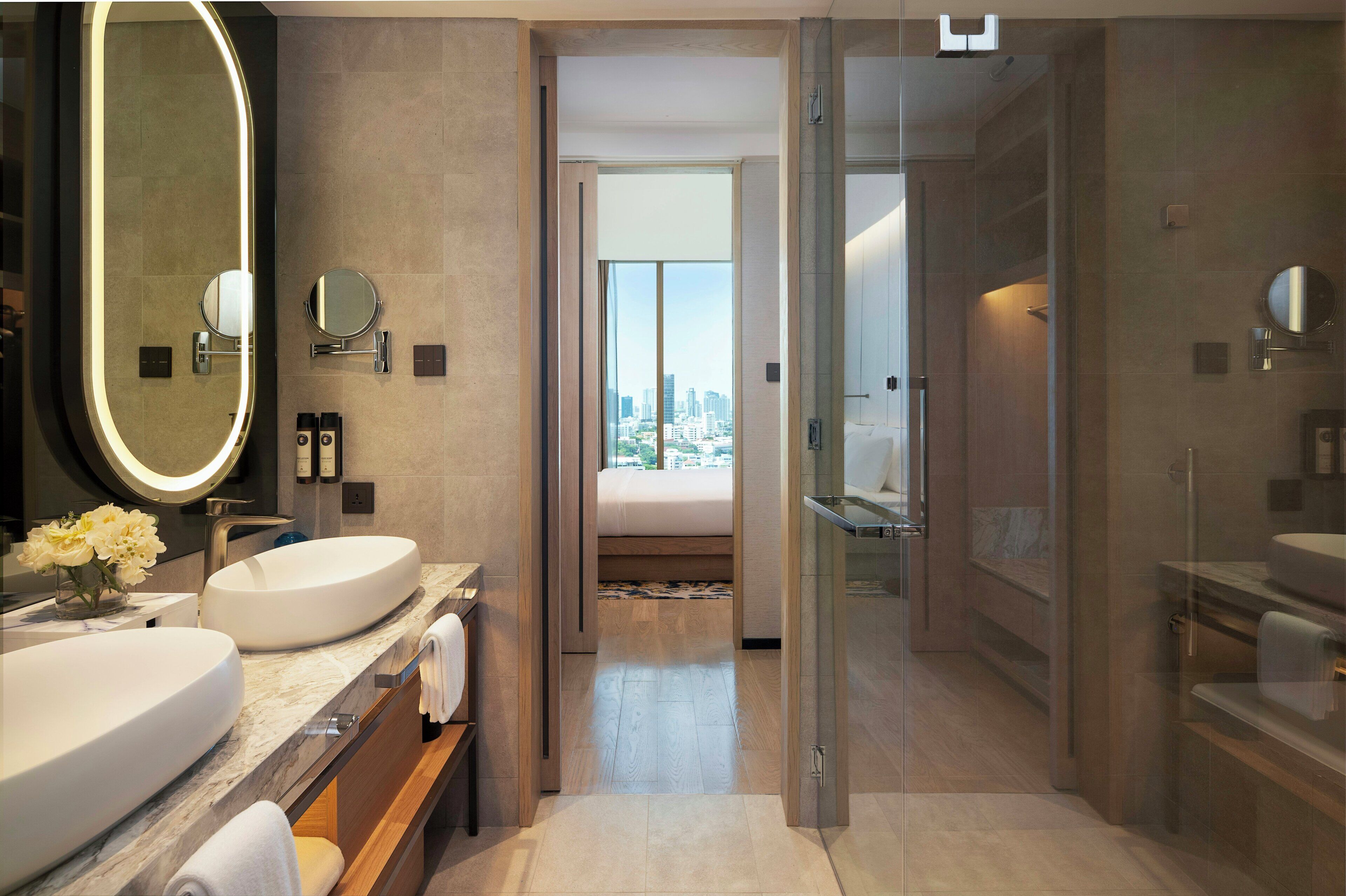 A modern bathroom with dual sinks, a large mirror, and a glass shower enclosure.