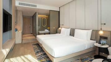 Una habitación de hotel moderna con una cama grande, mesitas de noche, un televisor y un baño visible a través de una puerta abierta.