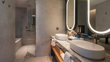 A modern bathroom with a glass-enclosed shower, two sinks, and a vanity with a mirror.