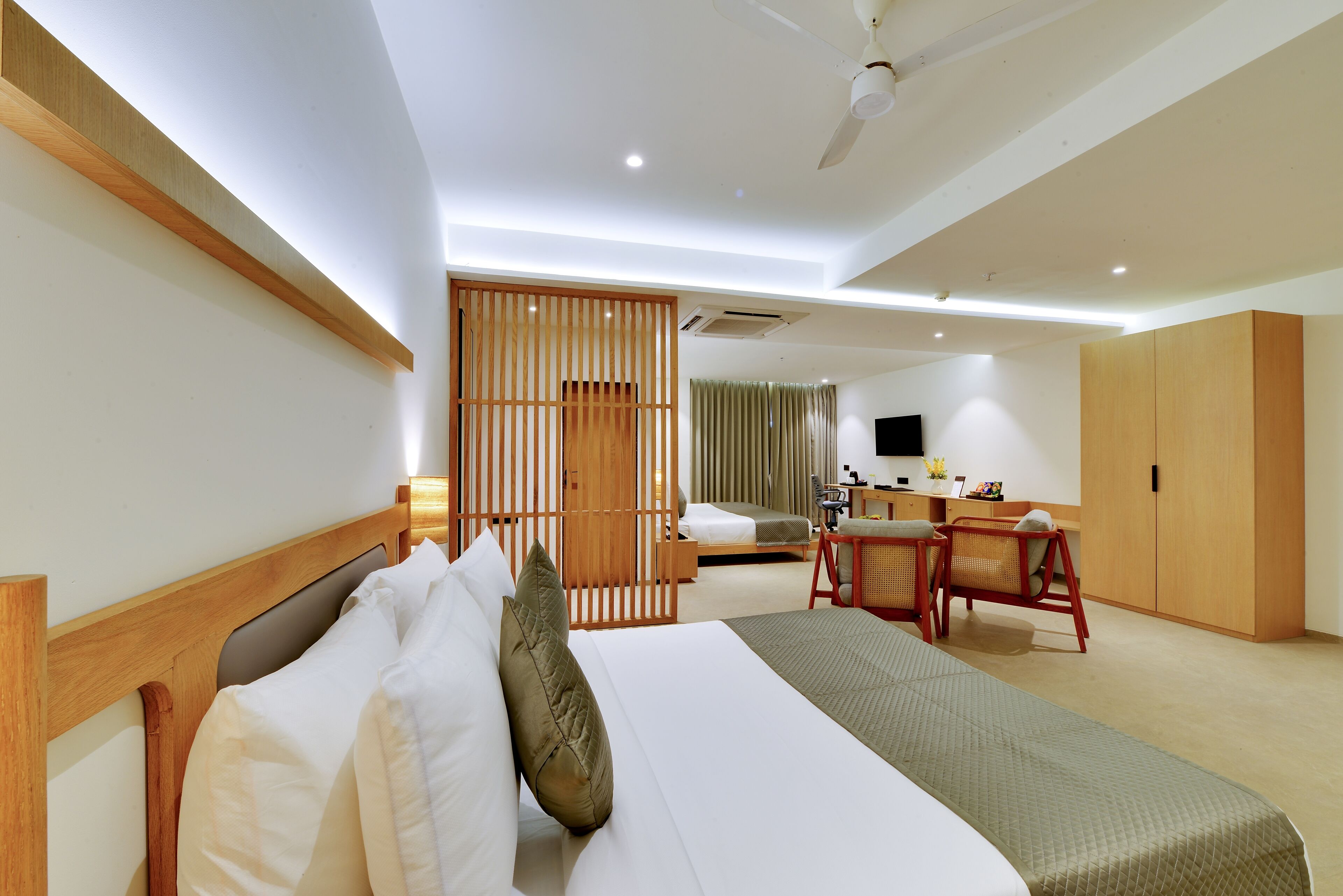 A hotel room with a large bed, a desk, a chair, and a wardrobe.