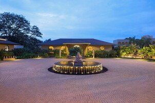 A courtyard with a Buddha statue in the center, surrounded by a circular water feature.