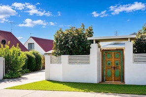 A residential property with a well-maintained lawn, a gated entrance, and a distinctive wooden door.