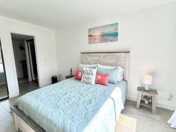 A bedroom with a bed, a nightstand, a lamp, and a painting on the wall. - GV 5525 Golf Course View Condo-Welcome to Paradise (Fort Pierce)