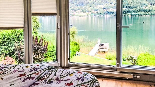 Une chambre dotée d’une grande fenêtre donnant sur un lac et une forêt.
