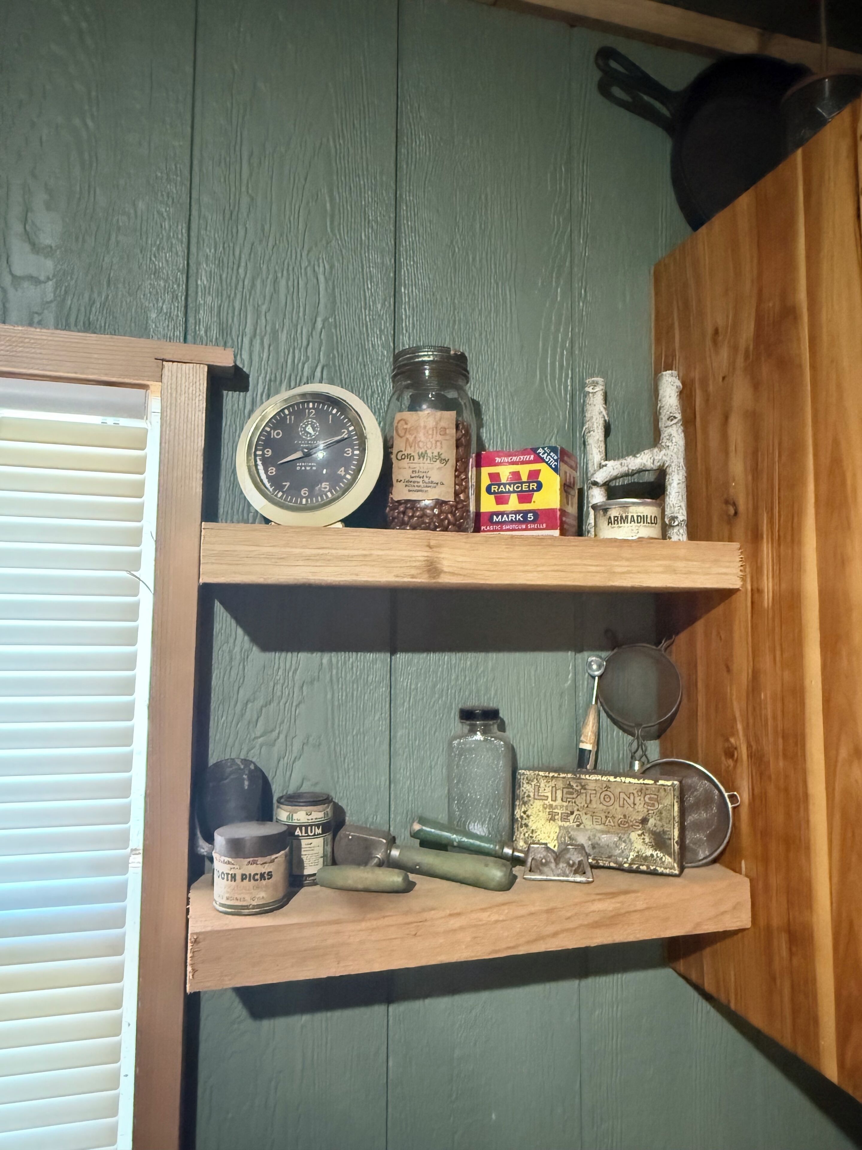 Una estantería con varios objetos, incluyendo un reloj, frascos y una caja etiquetada “Ranger”.