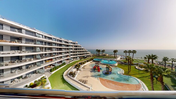 Un hôtel à plusieurs étages doté d’un espace piscine comprenant un toboggan aquatique et une plage.
