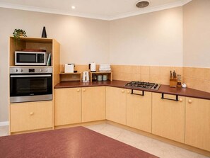 Une cuisine avec des meubles en bois, un four à micro-ondes, une cuisinière et une machine à café.