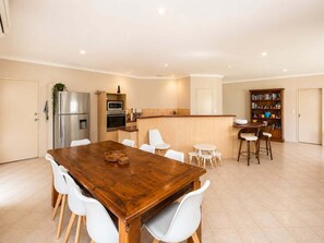Eine moderne Küche mit einem Holzespeisetisch, weißen Stühlen, einem eingebauten Backofen und einem Kühlschrank.