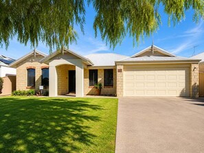 Ein zweistöckiges Haus mit Garage, Veranda und einem gepflegten Rasen.