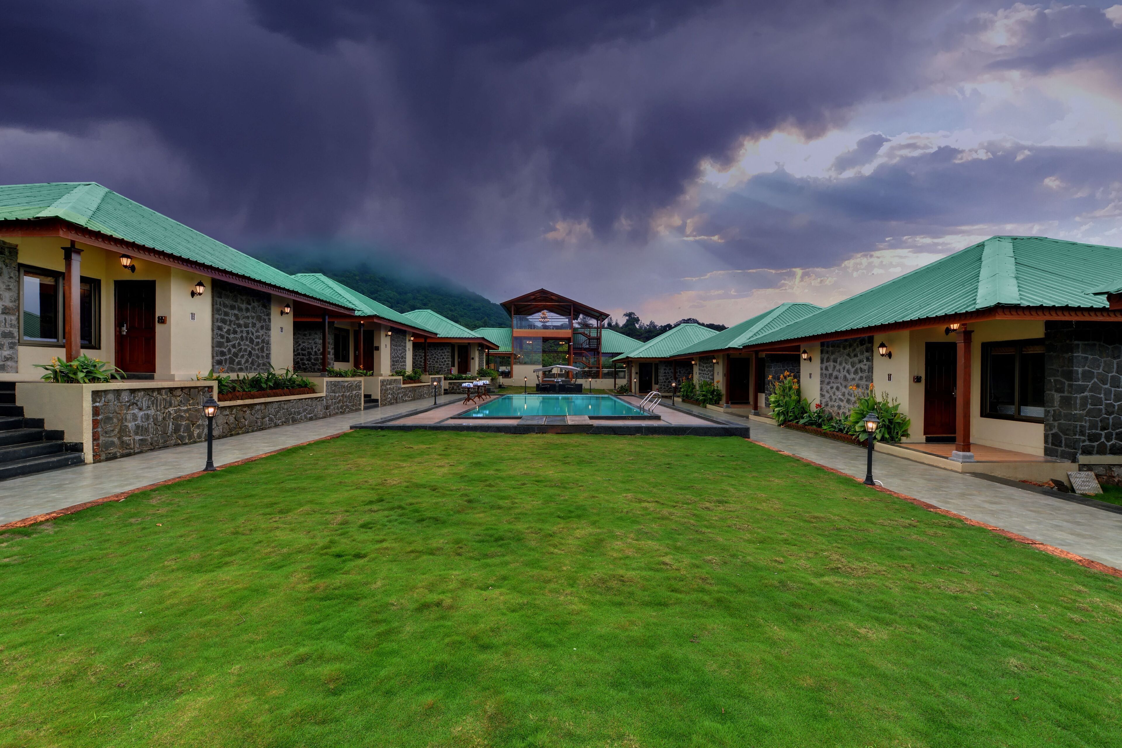 A resort with multiple buildings, a central pool, and a mountainous backdrop.