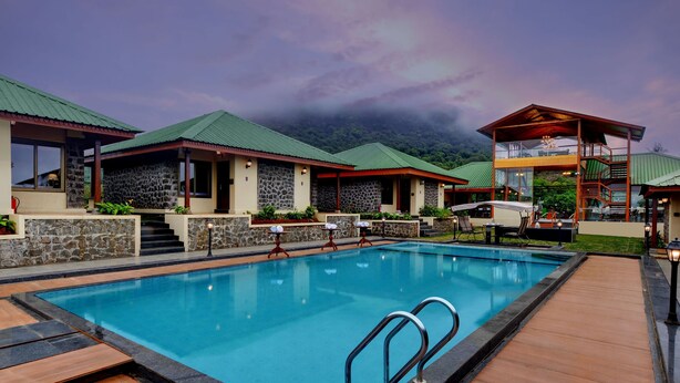 Ein Resort mit Schwimmbad, Gebäuden aus Stein und Holz und Blick auf Berge.