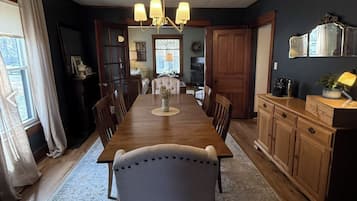 A dining room with a long wooden table, chairs, and a chandelier.