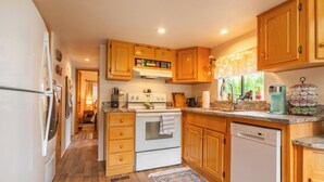 Une cuisine avec des meubles en bois, une cuisinière blanche et un lave-vaisselle.