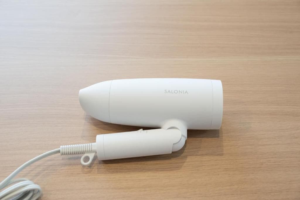 A white electronic device with a cable on a wooden surface.