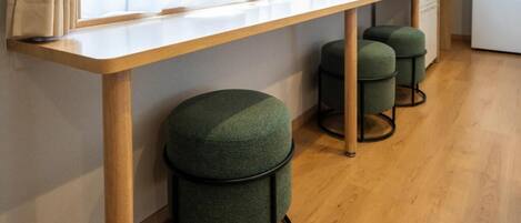 A kitchen with a wooden countertop, a window with curtains, and two green stools.