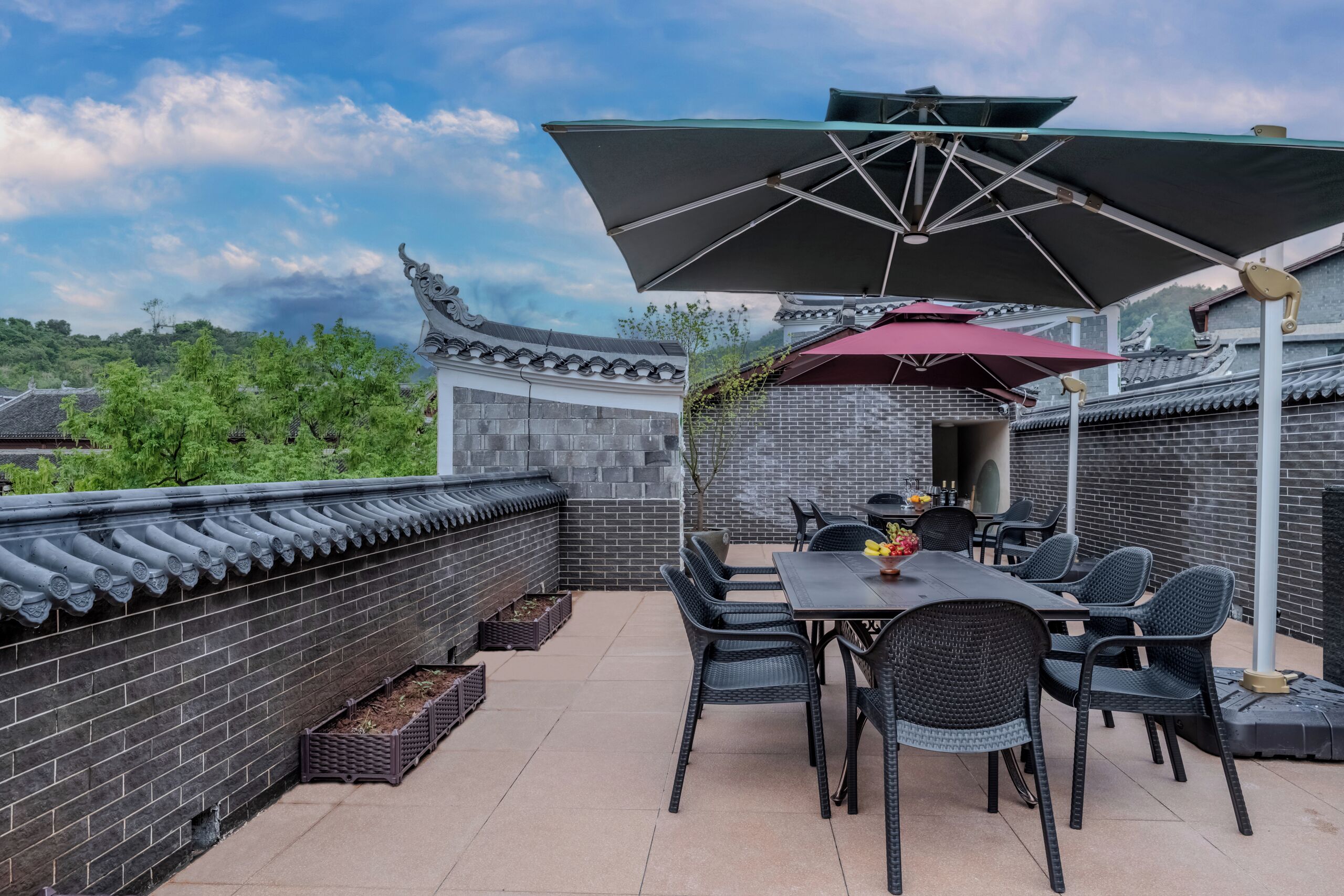 An outdoor patio with a table and chairs, a large umbrella, and a traditional-style building in the background.