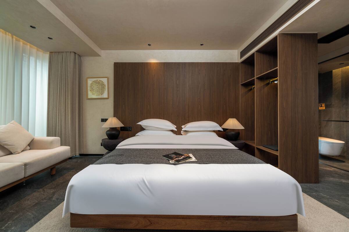Habitación de hotel con una cama grande, un sofá, un armario y un baño.