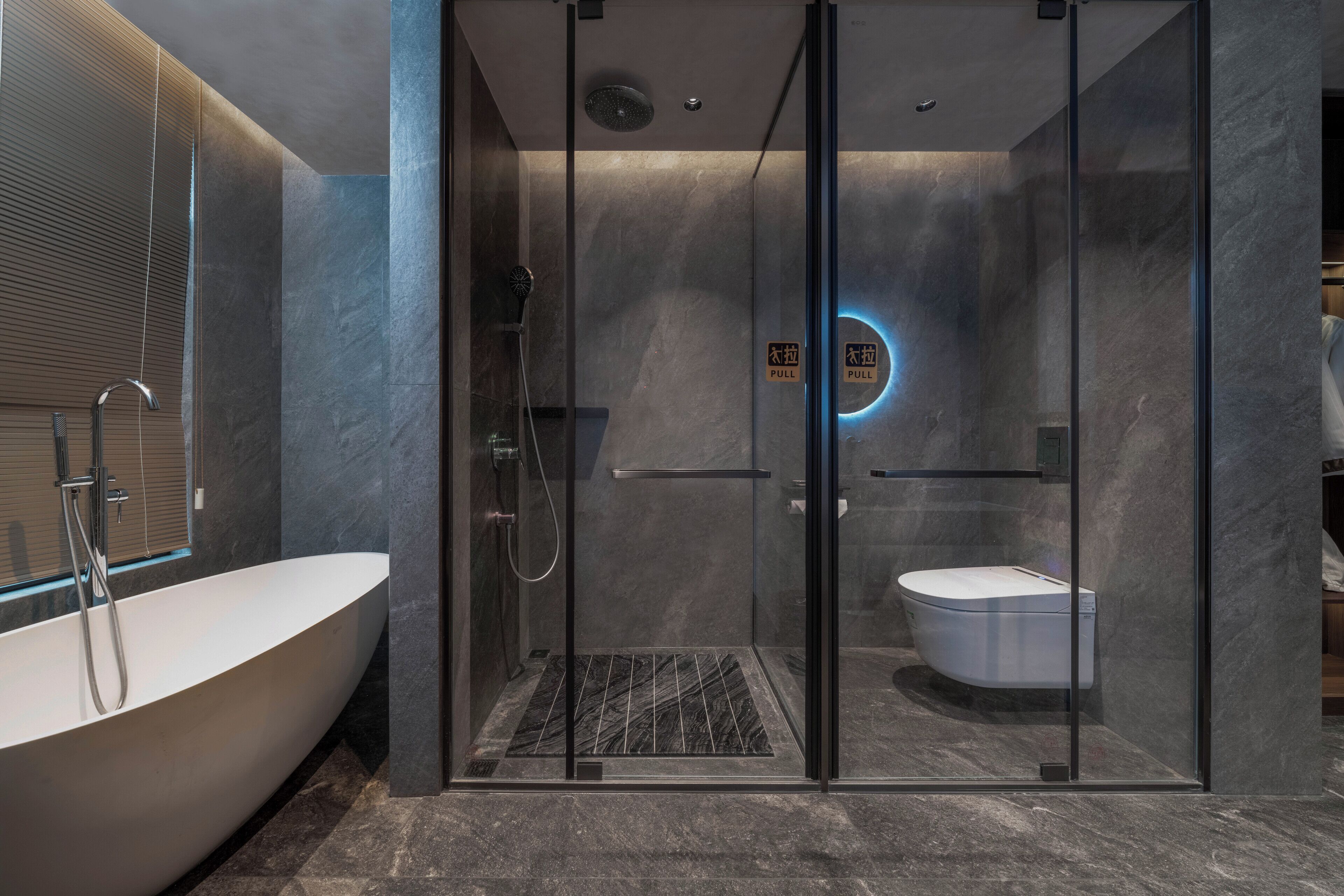 A modern bathroom with a glass-enclosed shower, a freestanding bathtub, and a toilet.