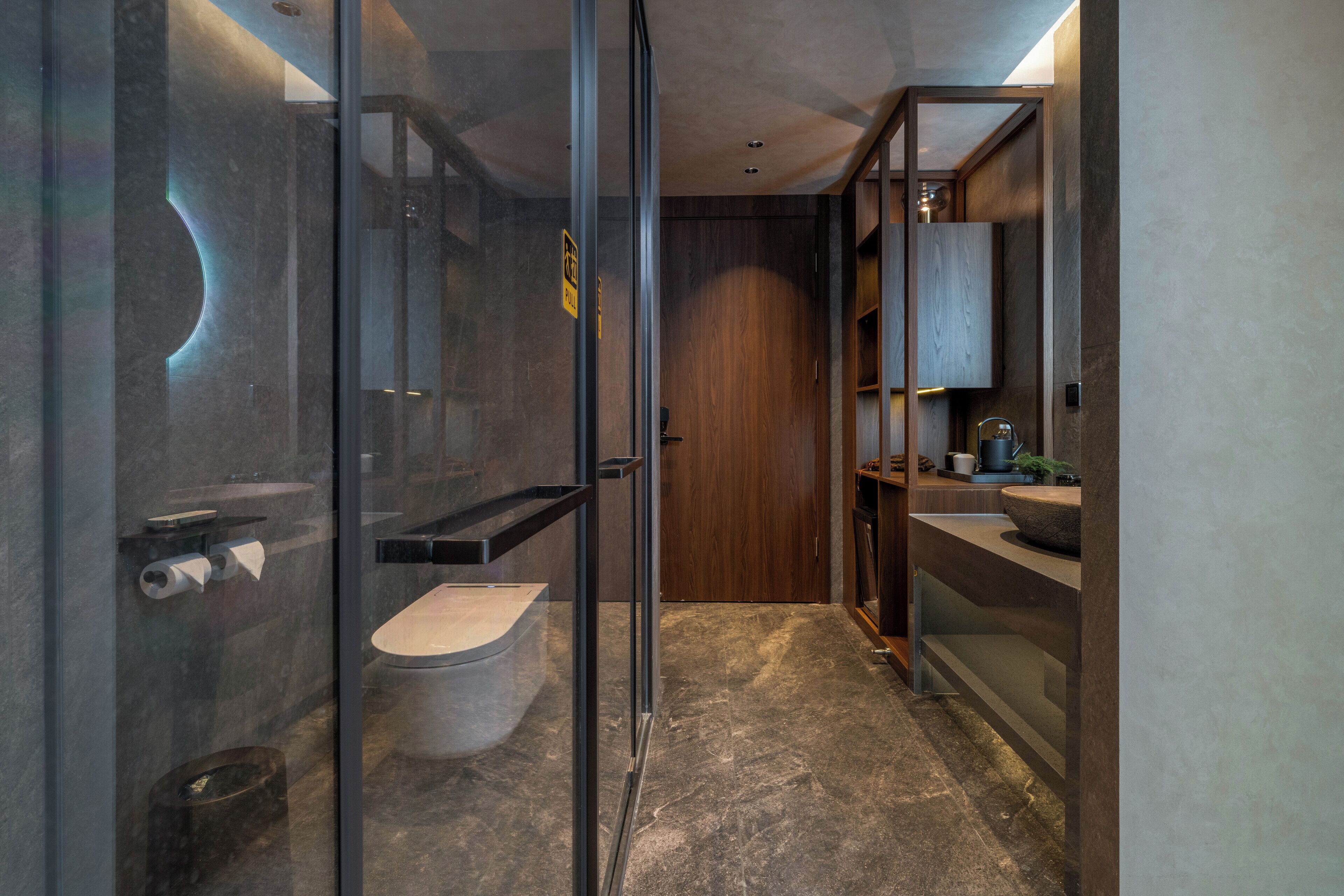 Une salle de bain moderne dotée d’une douche à parois de verre, de toilettes et d’un lavabo avec un plan de travail en bois.