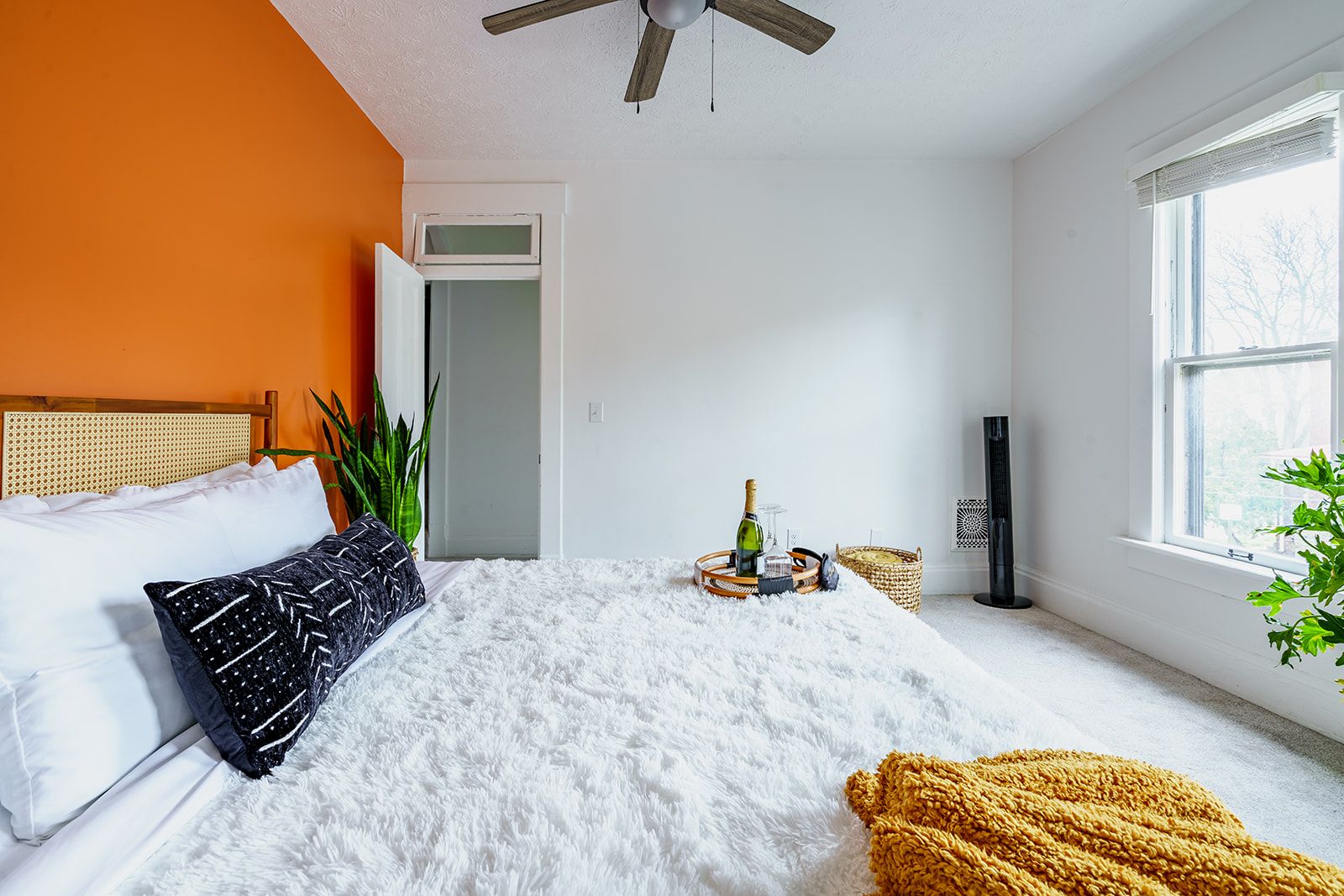 Un dormitorio con cama, ventilador de techo, ventana y puerta.