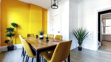 Un comedor con una mesa de madera y sillas amarillas, rodeado de plantas en macetas.