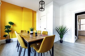 Un espace repas avec une table en bois et des chaises jaunes, entouré de plantes en pot.