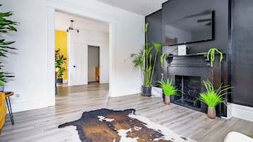 Una sala de estar moderna con chimenea, suelo de madera y varias plantas en macetas.
