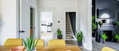 A modern dining area with a wooden table, yellow chairs, and potted plants.