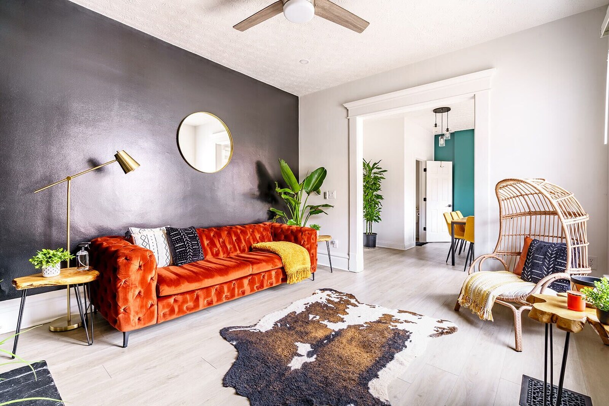 Un salon moderne avec un canapé, un tapis en peau de vache et un coin repas avec des chaises.