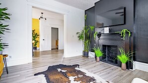 A modern living room with a fireplace, wooden flooring, and several potted plants. - Jungle House Boutique Residences – Downtown Columbus & Short North (Columbus)