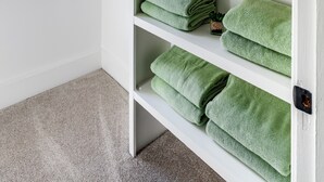 A white shelf with green towels, a white lamp, and small potted plants. - Jungle House Boutique Residences – Downtown Columbus & Short North (Columbus)