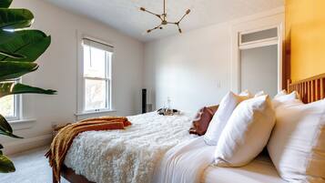 A bedroom with a bed, white bedding, a brown throw blanket, a ceiling fan, and a window.