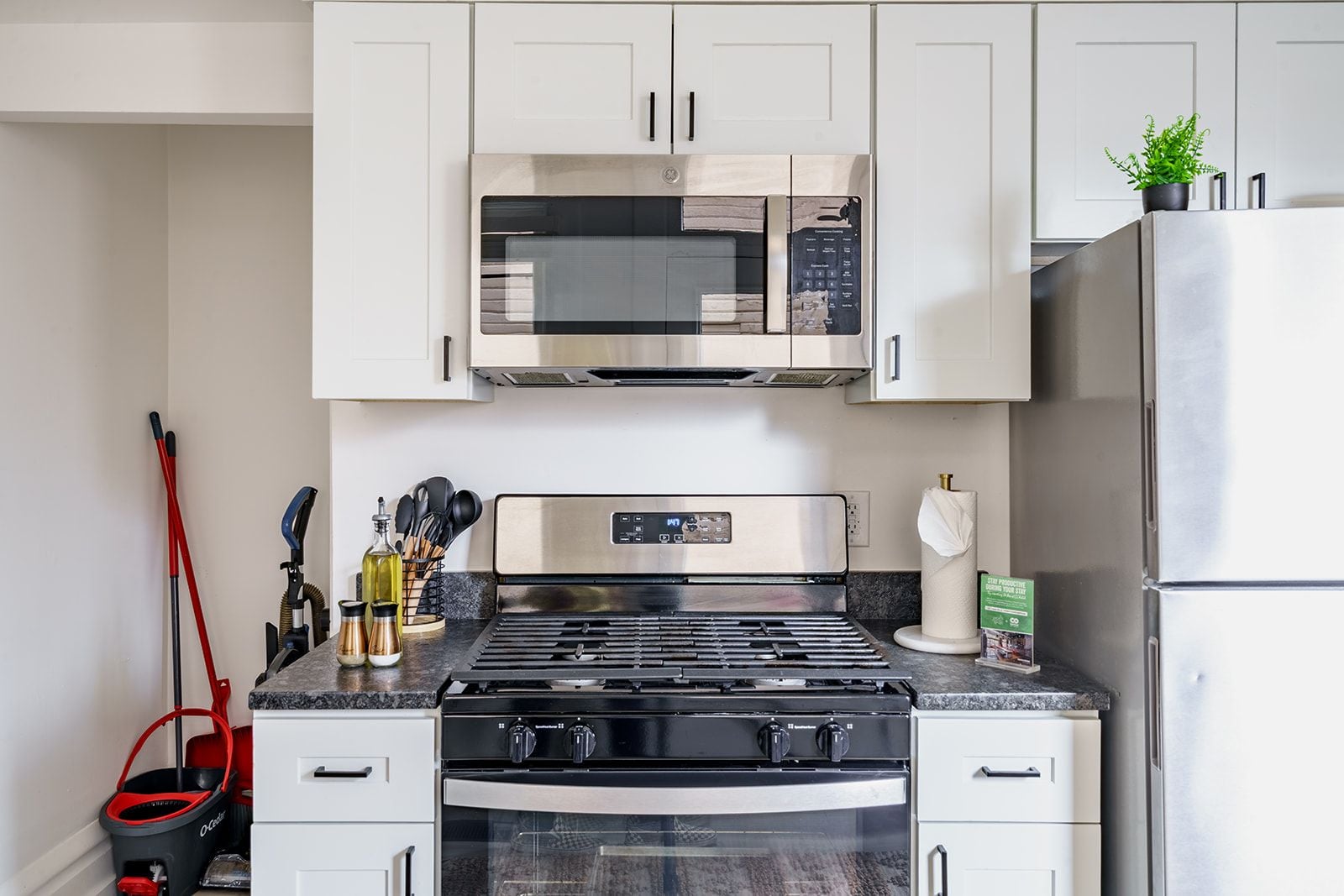 A kitchen with a stove, oven, microwave, and a refrigerator.