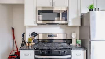 A kitchen with a stove, oven, microwave, and a refrigerator.