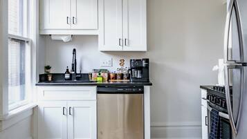 Eine moderne Küche mit weißen Schränken, einem Edelstahl-Geschirrspüler und einem eingebauten Backofen.