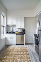 A modern kitchen with white cabinets, a stainless steel dishwasher, and a built-in oven.