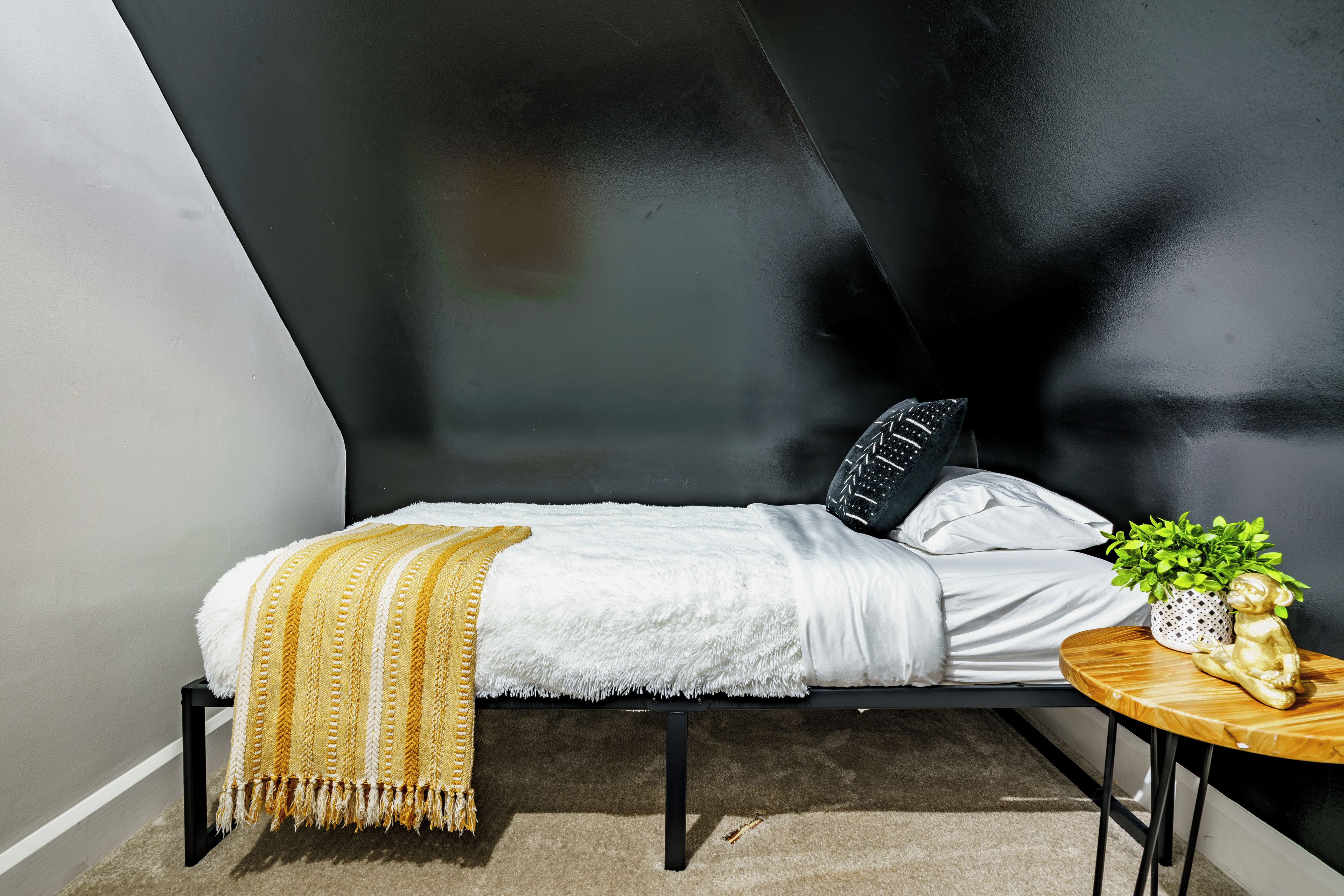 Una camera da letto moderna e accogliente con un letto, un comodino e una pianta in vaso.