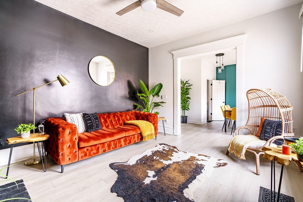 A modern living room with a sofa, a cowhide rug, and a dining area with chairs.
