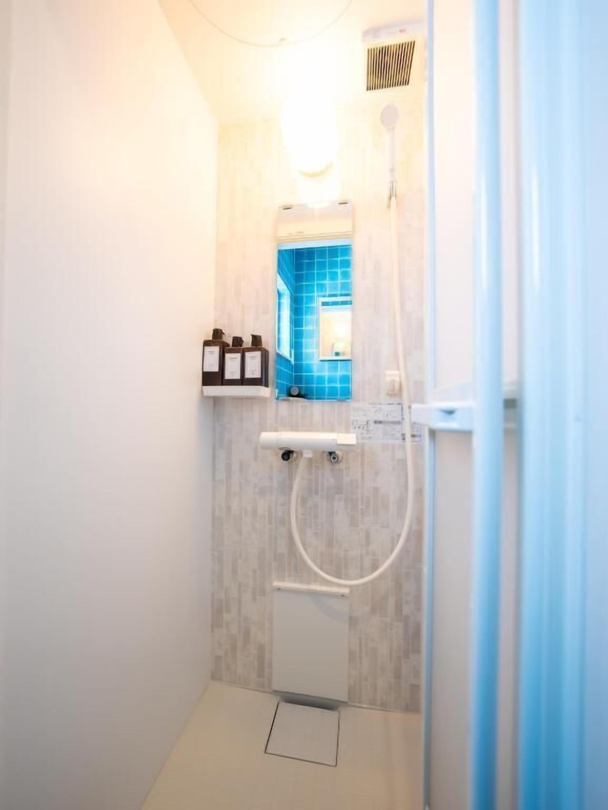 A small, modern bathroom with a shower, a towel rack, and a mirror.