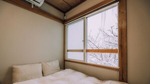 A bedroom with a large window, a bed, and a wooden ceiling. - 3BD Yuzawa Onsen Lodge - House B (Minamiuonuma)