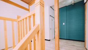 A wooden staircase leading to a room with a teal door and a white wall. - 3BD Yuzawa Onsen Lodge - House B (Minamiuonuma)