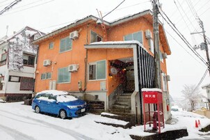 Un edificio a due piani con un idrante rosso e un'auto blu parcheggiata davanti.