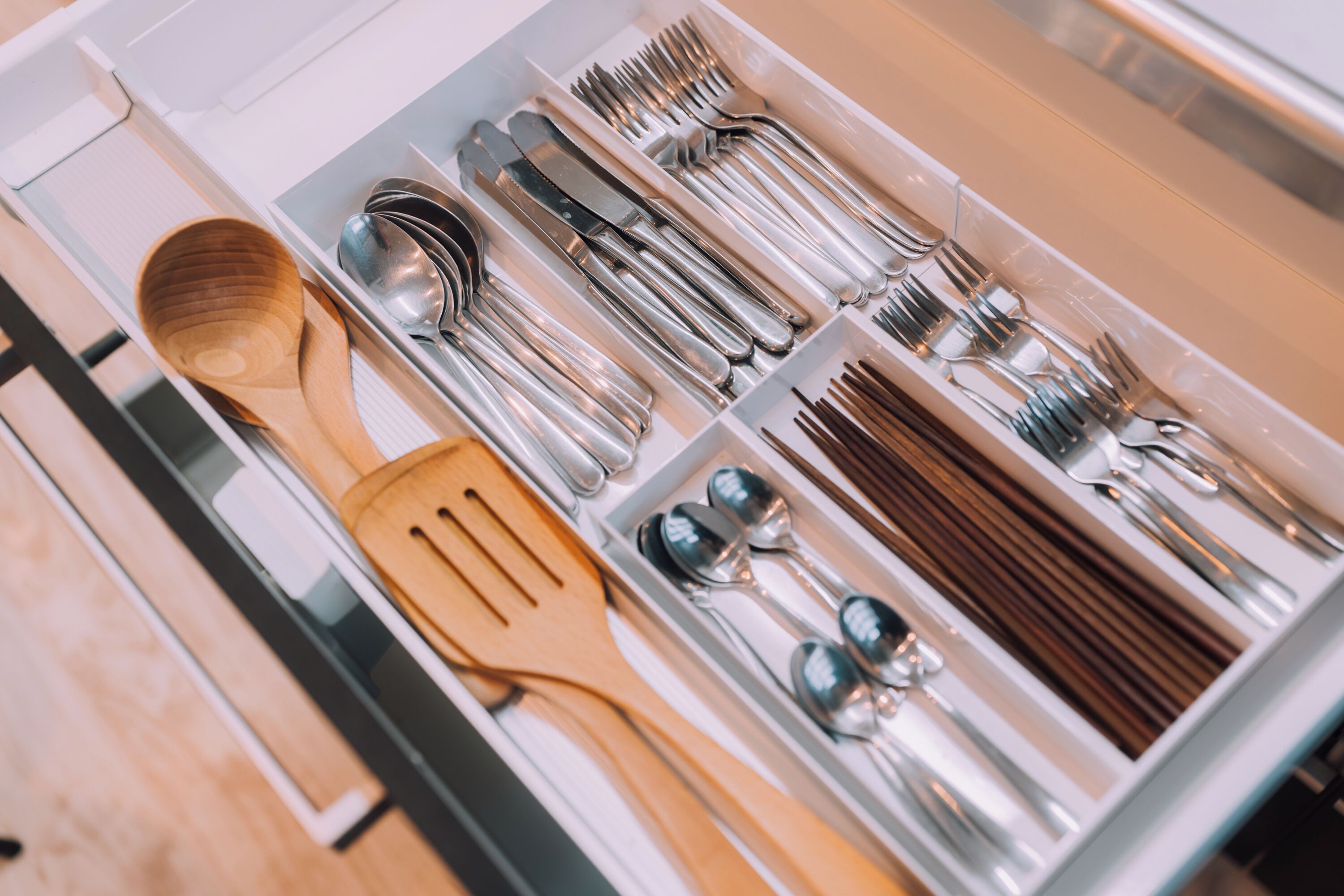 A drawer containing various utensils including wooden spoons, forks, knives, and spoons.