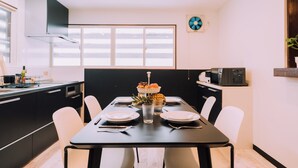 A modern kitchen with a dining table set for four, featuring a fruit bowl and glasses. - 3BD Yuzawa Onsen Lodge - House B (Minamiuonuma)