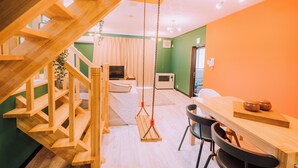 A wooden staircase leading to a loft area with a swing chair and a dining table with chairs. - 3BD Yuzawa Onsen Lodge - House B (Minamiuonuma)